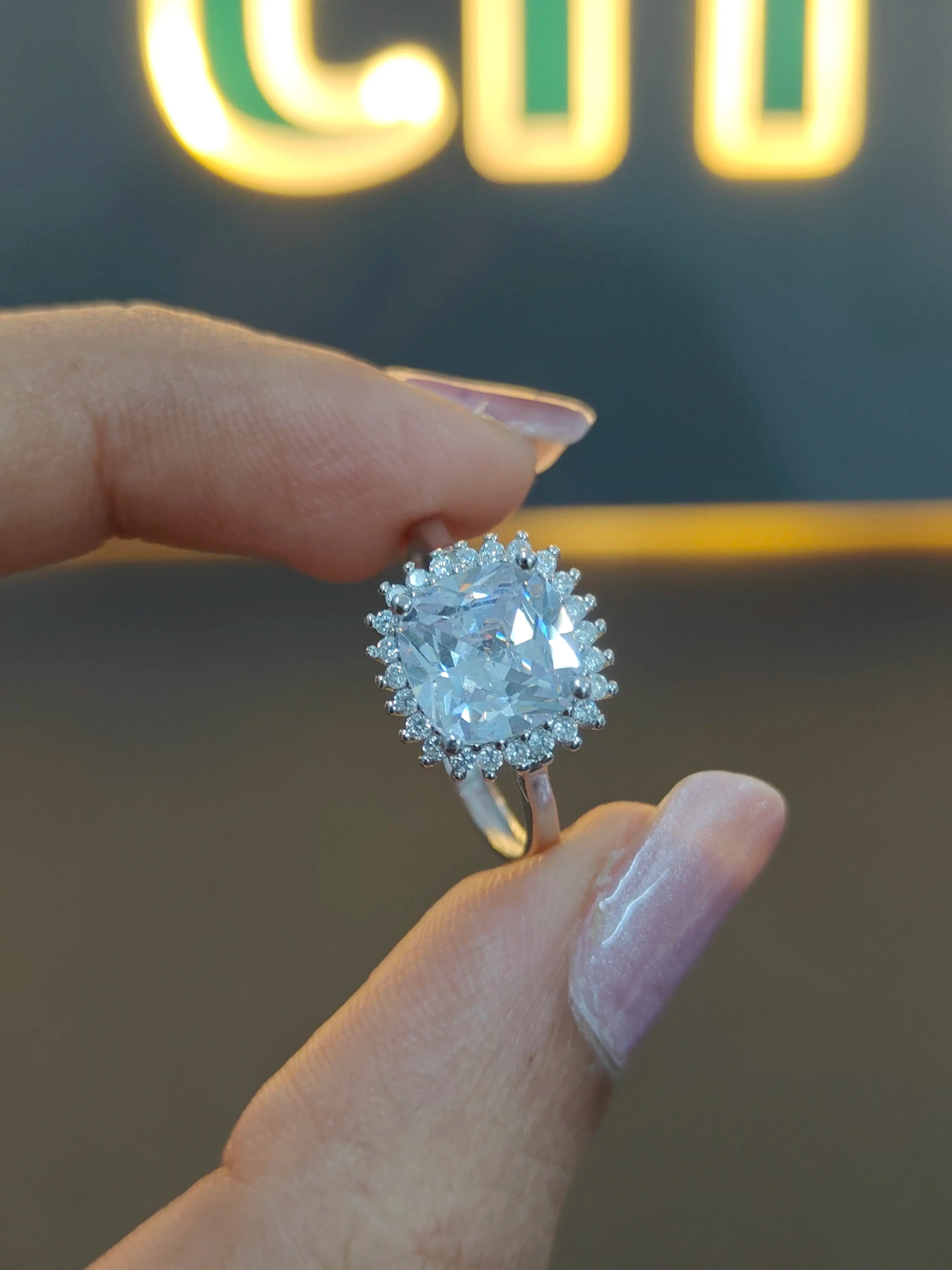 Diamond ring held by a hand with a blurred background